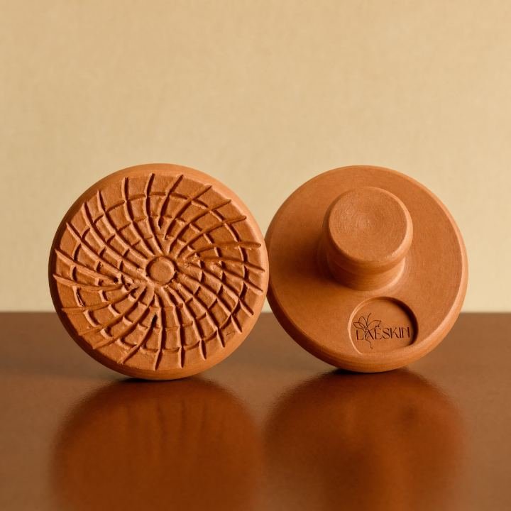 Deux accessoires ronds couleur terre cuite posés sur une surface brillante