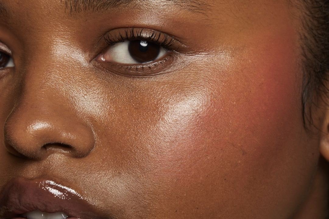 Gros plan d'un visage à la peau lumineuse avec une touche de blush rose